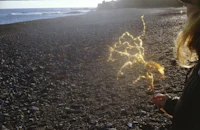 a woman holding a stick on a beach