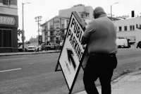 a man standing on the side of the street with a sign