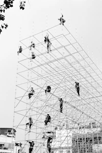 a black and white photo of people working on scaffolding